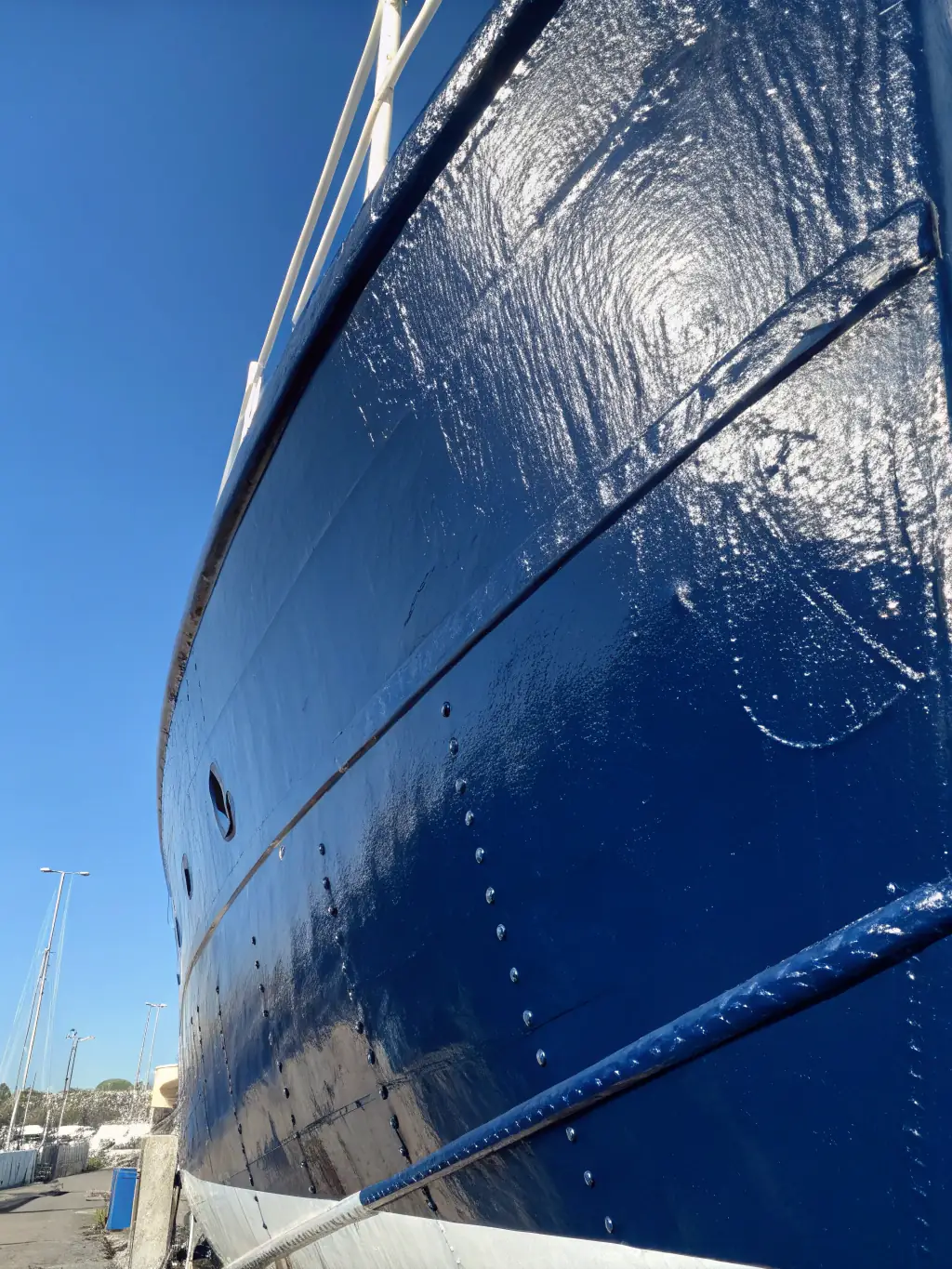 A high-definition, close-up shot of a freshly ceramic-coated boat hull, showcasing the glossy, reflective surface and water beading effect, emphasizing the protective qualities of the coating.